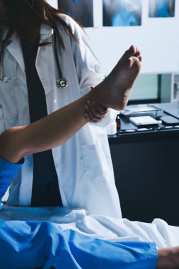 Hastane odasında yaralı bir kadının ayak bileğini inceleyen ve destekleyen doktor, burkulma ya da kırık için tıbbi yardım ve tedavi sunuyor.