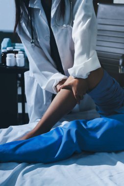 Hastane odasında yaralı bir kadının ayak bileğini inceleyen ve destekleyen doktor, burkulma ya da kırık için tıbbi yardım ve tedavi sunuyor.