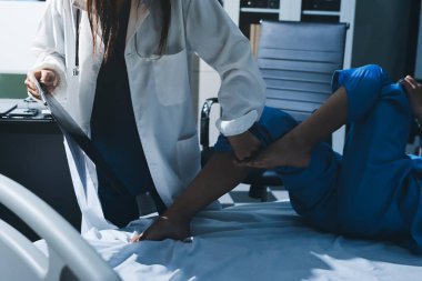 Hastane odasında yaralı bir kadının ayak bileğini inceleyen ve destekleyen doktor, burkulma ya da kırık için tıbbi yardım ve tedavi sunuyor.