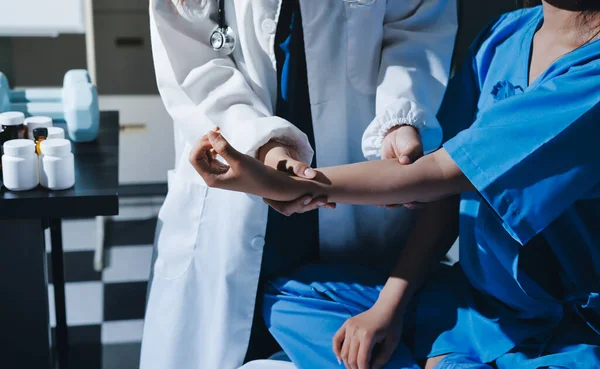 Hastane odasında hastanın dirseğini muayene eden doktor.