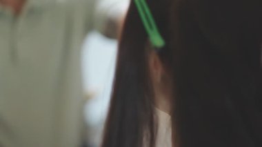 Usta kadın kuaför, kuaförde yıkandıktan sonra kızın saçını saç kurutma makinesiyle kurutur..