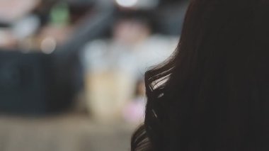 Usta kadın kuaför, kuaförde yıkandıktan sonra kızın saçını saç kurutma makinesiyle kurutur..