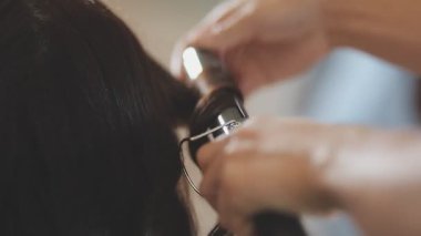 Usta kadın kuaför, kuaförde yıkandıktan sonra kızın saçını saç kurutma makinesiyle kurutur..