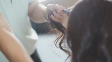 Usta kadın kuaför, kuaförde yıkandıktan sonra kızın saçını saç kurutma makinesiyle kurutur..