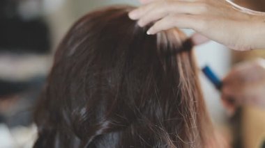 Usta kadın kuaför, kuaförde yıkandıktan sonra kızın saçını saç kurutma makinesiyle kurutur..