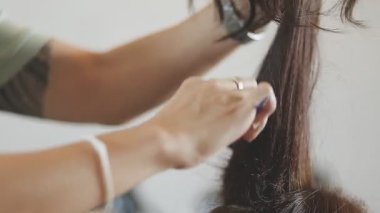 Usta kadın kuaför, kuaförde yıkandıktan sonra kızın saçını saç kurutma makinesiyle kurutur..