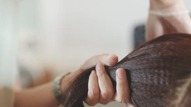 Usta kadın kuaför, kuaförde yıkandıktan sonra kızın saçını saç kurutma makinesiyle kurutur..