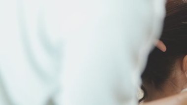 Usta kadın kuaför, kuaförde yıkandıktan sonra kızın saçını saç kurutma makinesiyle kurutur..