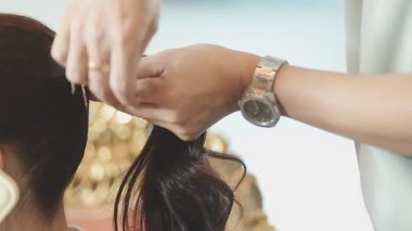 Usta kadın kuaför, kuaförde yıkandıktan sonra kızın saçını saç kurutma makinesiyle kurutur..