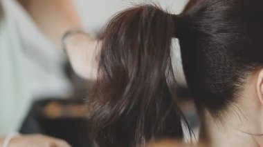 Usta kadın kuaför, kuaförde yıkandıktan sonra kızın saçını saç kurutma makinesiyle kurutur..