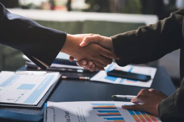 Genç iş adamları ofiste el sıkışıyor. Başarılı toplantı sona eriyor. Üç kişi. Geniş ekran panoramik