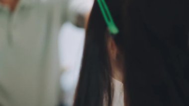 Kadın kuaför, kuaförde esmer saçlı genç bir kadına saç stili yapıyor..