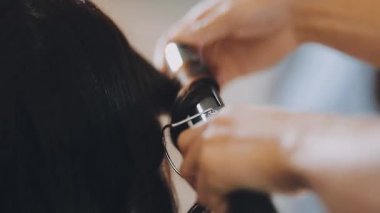 Kadın kuaför, kuaförde esmer saçlı genç bir kadına saç stili yapıyor..