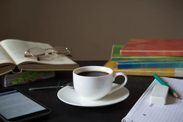 Café frente a los libros de texto, smartphone y portátil en una mesa de madera oscura . — Foto de Stock