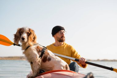 Gölde kanoda köpeği olan bir adam. Kano kayığında spanyel ile gezen genç bir erkek, evcil hayvanlarla, arkadaşlıkla, macera köpekleriyle aktif boş zamanı var.