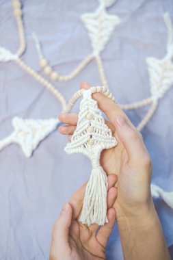 El yapımı yeni yıl süslemeleri kadınların elinde. Kişi, köknar ağacı şeklinde bir Noel çelengi tutar. Kış tatili konsepti için evi dekore etmek