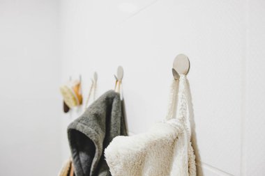 Banyoda kancaya asılı beyaz bir banyo bornozunun yakın plan görüntüsü. Modern banyo odasının ayrıntılarının minimalist görüntüsünü paylaşın.