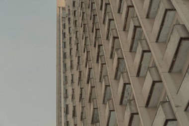 Terk edilmiş bir bina temiz gökyüzüne karşı. Sovyet modernist mimarisi, sıkıntılı beton ev