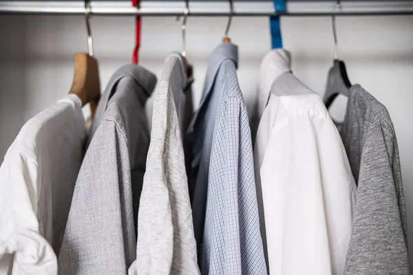 一排排的棉质衬衫和T恤衫挂在衣橱里 简朴休闲的单色风格 相似的服装选择 纺织品 — 图库照片