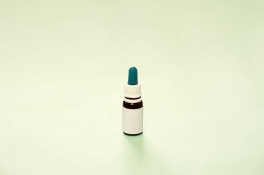 Tarafsız yeşil zeminde genel bir yağ şişesi. CBD veya THD yağı, doğal sağlık ürünleri, sakinleştirici takviyeler, kopyalama alanı arka planı