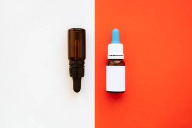 Canlı beyaz ve kırmızı arka plana karşı iki şişe damlatıcıyla. Temel, cbd veya thd yağları küçük şişelerde, arkaplanı kopyala