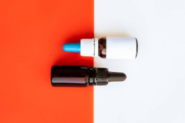 Canlı beyaz ve kırmızı arka plana karşı iki şişe damlatıcıyla. Temel, cbd veya thd yağları küçük şişelerde, arkaplanı kopyala