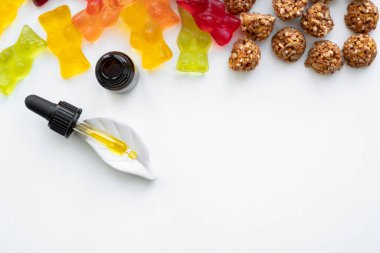Jelibon ayılar, kenevirli kurabiyeler ve beyaz arka planda cbd yağ düşürücü. Jelatinli jelibon ayıcıkları ve temel yağ pipeti arkaplanı olarak THD veya cbd tatlıları: yenilebilir gıda takviyelerinin sakinleştirilmesi