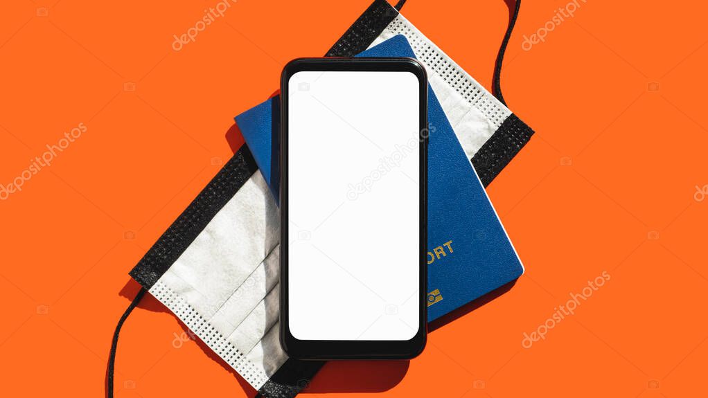 Modern travel concept, blank white smartphone screen. Generic phone display, face mask and a biometric passport in bright red backdrop, copy space