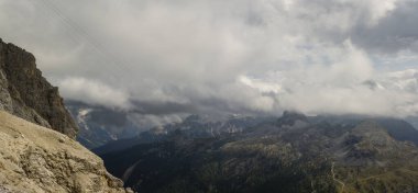 Kara kara düşünen bulutlar, Dolomitlerin kireçtaşı zirvelerini kaplıyor, katmanlı dağ sırtları sise dönüşüyor, aşağıdaki derin ormanlık vadiler, engebeli yamaçları takip eden sarmal alp yollar, kayan ışık, yoğun dağlık atmosfer yaratıyor. İtalya 'da yakalandı. Dolomit