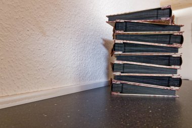 Several ribbon laced scrapbooks rest in a tidy pile on the desk. Black pages peek from the covers while slim bows line the spines, ready for prints tickets and small keepsakes.