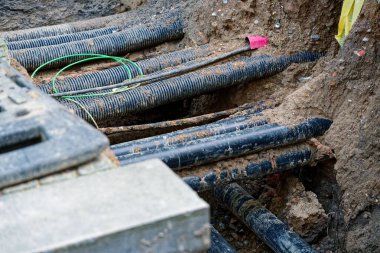 Kazılan bir yol, gömülü hizmetlerin katmanlarını, bölge ısıtma borularını ve siperlerden geçen kabloları, su hatlarını ve toprak, taze toprak ve işaretleyicileri açığa çıkarıyor.