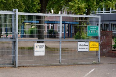 Okul zemininin yanında Spielplatz Schulgelaende ve Feuerwehrzufahrt panelleri bulunan birkaç tabela bulunur. Simgeleri ve okları temizle sessiz yol boyunca erişim ve güvenlik için kurallar belirle.