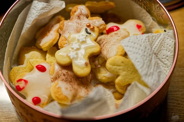 İnsan şeklinde metal bir teneke kutu ev yapımı kurabiyelerle doludur. Canlı stil, yıldızlar ve gözler, krema ve parlak serpiştirmeler. Neşeli çeşitlilik tatlı bir tadı davet eder.