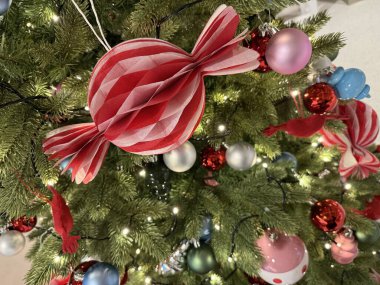 Kırmızı şeker süsü ve renkli takılarla süslenmiş Noel ağacı. Kutlama yaşam tarzı ve tasarım temaları için mükemmel neşeli bir tatil ortamı.