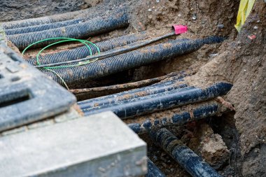 Kazılan bir yol, gömülü hizmetlerin katmanlarını, bölge ısıtma borularını ve siperlerden geçen kabloları, su hatlarını ve toprak, taze toprak ve işaretleyicileri açığa çıkarıyor.