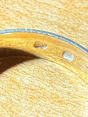 Üzerinde 585 Hallmark işaretiyle işlenmiş altın bir yüzüğün detaylı görüntüsü. Aşkın, değerin, orijinalliğin, işçiliğin ve sonsuz lüksün sembolü. Mücevherler, romantizm ve finans konuları için mükemmel.