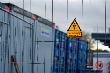 Tel örgülü tel örgüler siyah yıldırımlı, parlak sarı bir üçgen işareti taşır ve Alman metin hochspannung lebensgefahr, cesur uyarı yüksek voltaj gerektirir ve mesafe ve saygı gerektirir..
