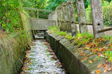Ostseebad Flensburg ormanındaki küçük bir köprünün altında yosun kaplı beton duvarlar arasında dar bir su kanalı var. Doğa mühendisliği, su akışı ve seyahat gibi konular için mükemmel..