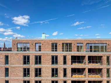 Geniş cam açıklıklarla yeni bir tuğla cephesi yükselir, temiz çizgiler uzun camları çerçeveler ve sokak tarafı parlak yeni ve sakin görünür içinde cömert bir ışık vardır..