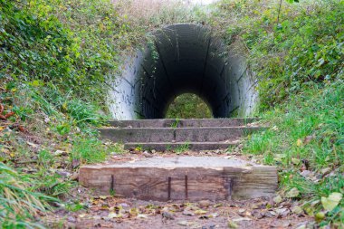 Küçük yarım yuvarlak bir tünel çimenli bir tepenin içinden açılır ve bir dizi beton basamak girişe tırmanır, düzgün bir yol höyük boyunca kısa bir ayak yolu için pratik ve düzenli hisseder..