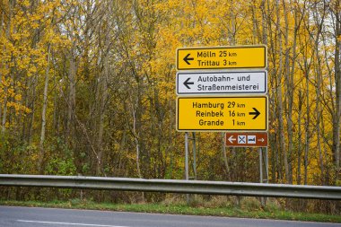 Otoyolun üzerinde mavi bir işaret var, Moelln ve Trittau 'ya doğru giden iki sol ok, Hamburg Reinbek ve Grande' ye giden yolu gösteren bir sağ ok var..