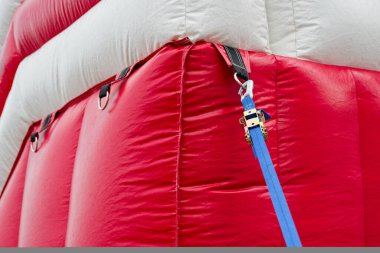 Kırmızı ve beyaz şişirilebilir bir çadır, şekli hava ve birkaç mavi iple sabit durur, bu da açık bir çalışma gününde geçici bir tıbbi ya da komuta sığınağı olduğunu gösterir..