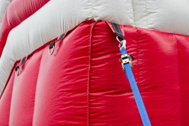 Kırmızı ve beyaz şişirilebilir bir çadır, şekli hava ve birkaç mavi iple sabit durur, bu da açık bir çalışma gününde geçici bir tıbbi ya da komuta sığınağı olduğunu gösterir..