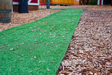 Alman noel pazarında gevşek odun parçaları zemini kaplarken, yeşil paspas dar bir şerit taze çimen gibi görünüyor, ziyaretçilere tribünler arasında nazikçe yol gösteriyor..