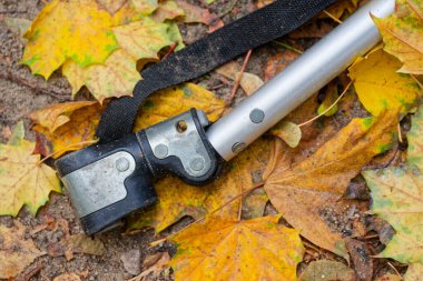 Renkli sonbahar yaprakları üzerinde dinlenen metal eklem bağlayıcısı açık hava ekipmanlarını sembolize eder bakım işi dayanıklılığı ve mevsimsel endüstriyel kavramları kullanır