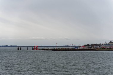 Limanda, iskelenin yanında su ve dikey direklerle bir gemi duruyor. Denizcilik altyapısını ve demirleme alanını gösteren sakin bir kenetlenme sahnesi oluşturuyor..