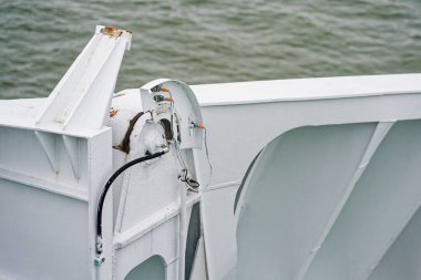 Beyaz boyalı bir gemi duvarı, teknik servis kullanımı için panele monte edilmiş kontrol ya da güvenlik bileşeni gibi görünen kabloları ve donanımları olan metal bir cihaz taşıyor..