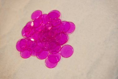 Parlak pembe tombala jetonları nötr bir yüzeye saçılmış, tombala oyunları, masa oyunları, kumarhane temaları, olay görselleri ve oyuncu tasarım şablonları için ideal