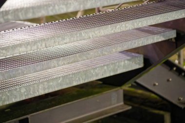 Açık şebeke merdiven izleri toprak ve su döken bir ağ deseni oluşturur. Botlu işçiler için tutunma ve drenaj sağlar..