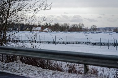 A7 E45 otobanı boyunca, her biri karla kaplanmış güneş panellerinin düzenli sıralarda durduğu açık arazileri korkuluklar oluşturarak, sakin bir kış yenilenebilir enerji manzarası oluşturur..